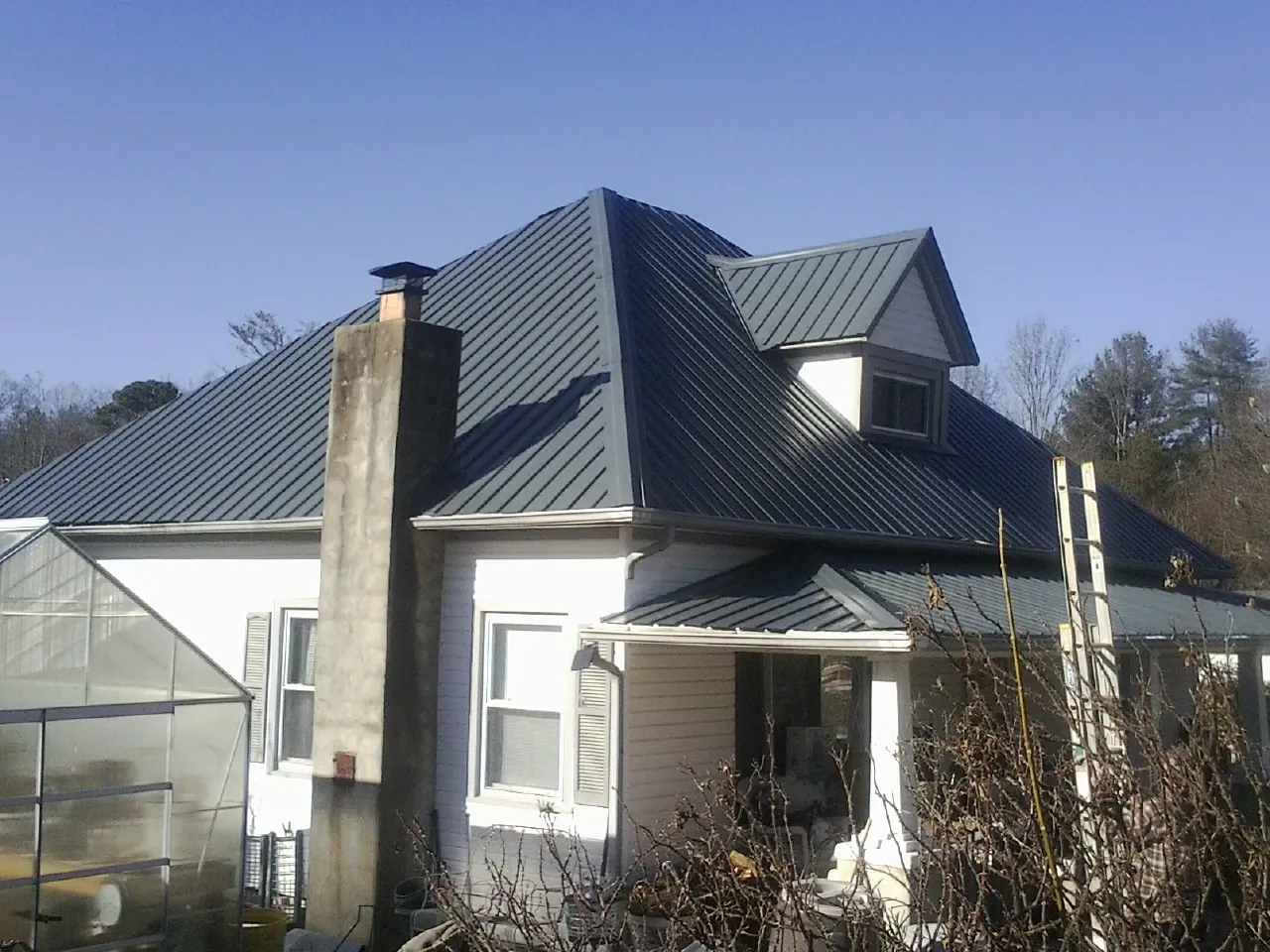 Dark blue standing seam metal roof on a white farmhouse with dormer — Slate & Tile Roof Repair by Roofing Brothers in Chapmansboro