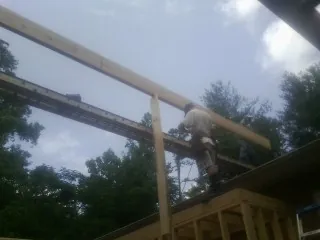 Carpenter setting a ridge beam over a new addition frame — Ice Dam Removal by Roofing Brothers in Chapmansboro