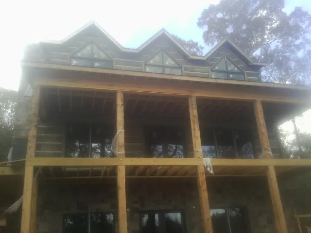 Dormers and porch framing on a large log home under construction — Roof Coating work by our crew in Chapmansboro