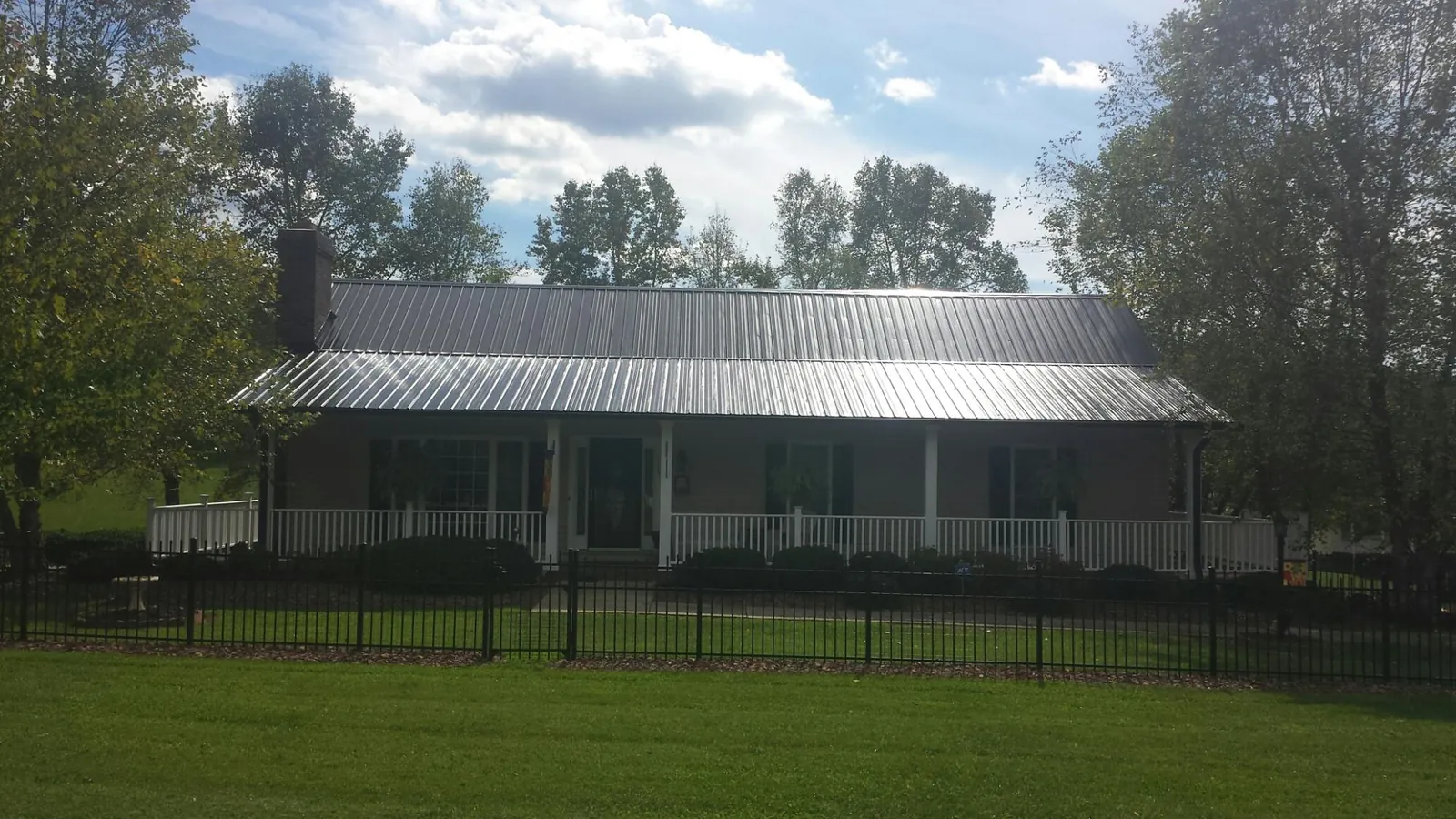 Gray metal roof on a brick ranch with a full width front porch — Gutter Guard Installation work by our crew in Chapmansboro