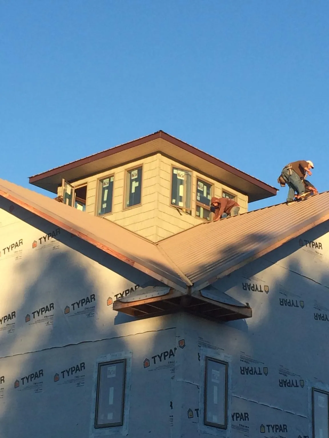 Roofers working around a rooftop cupola on a new metal roof at sunset — Roof Waterproofing in Chapmansboro by Roofing Brothers